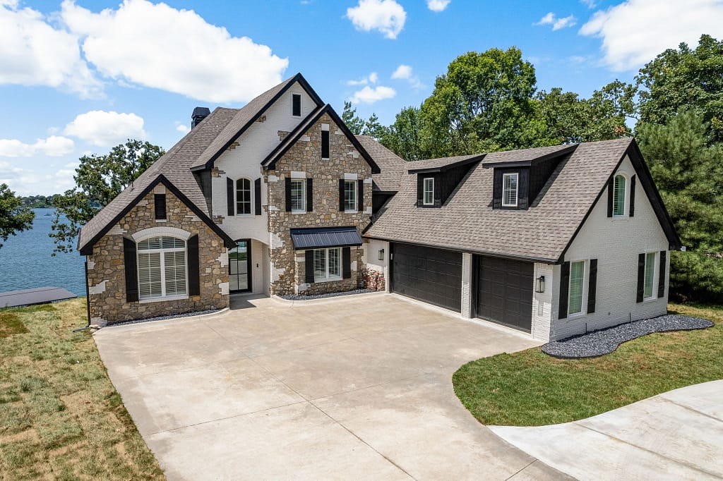 Large home with white brick exterior on a lake after remodel