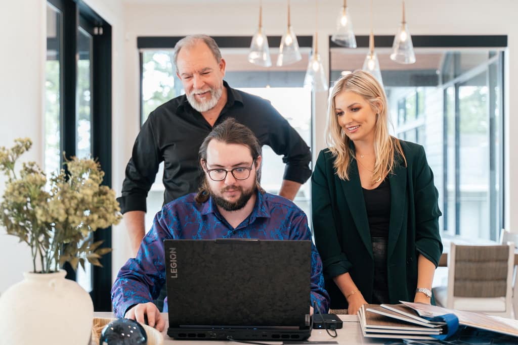 Reid, Kim, and Maceon collaborating around a laptop.