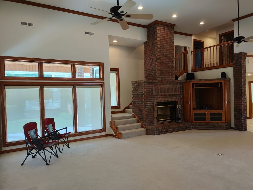 Large living room with fireplace and balcony above before remodel