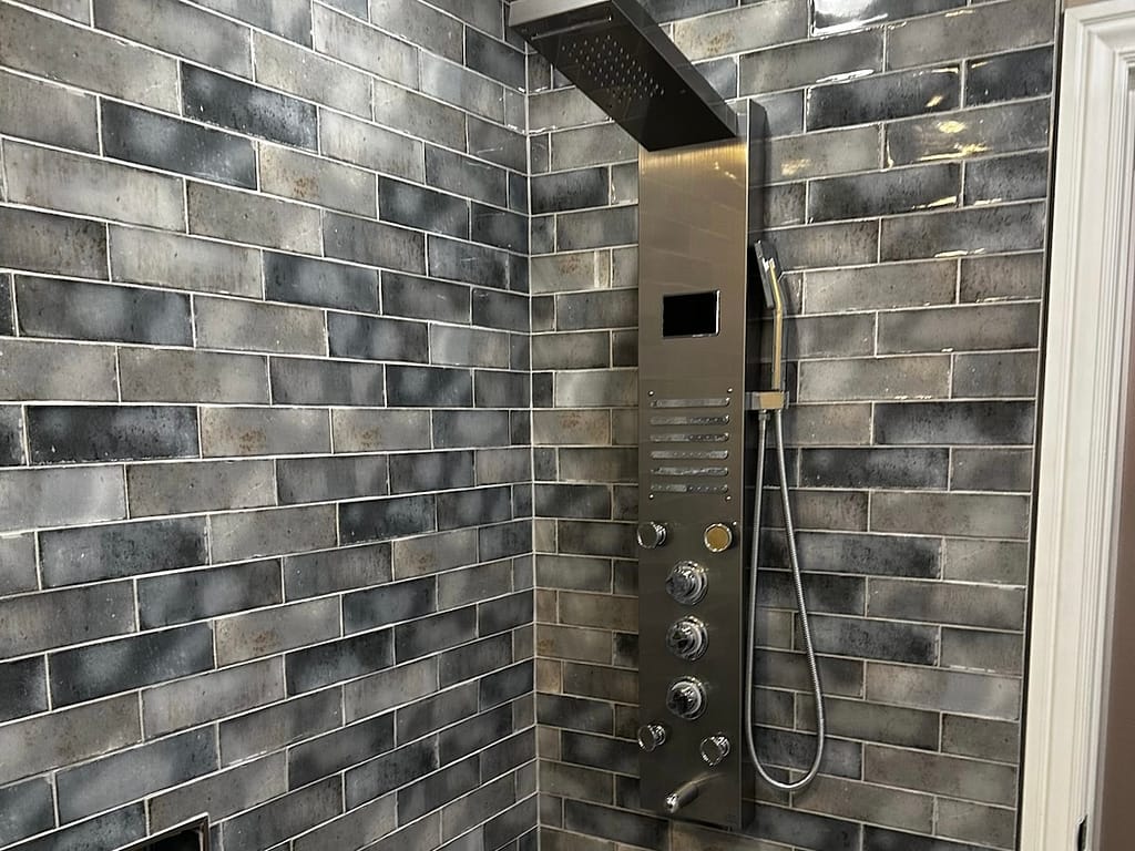 Bathroom shower with shower tower and grey tile after remodel