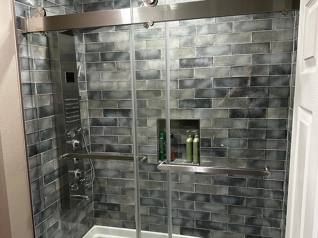 Bathroom shower with sliding glass door and grey tile after remodel