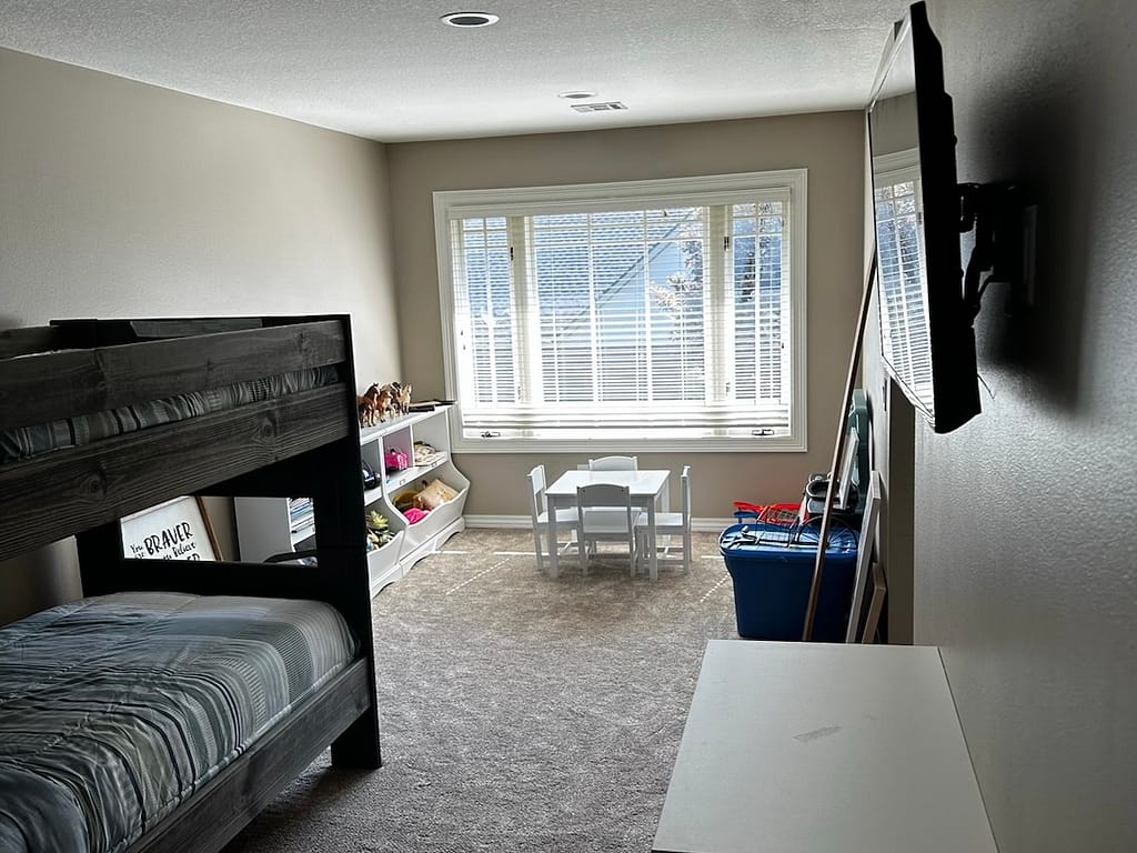 Bedroom with bunkbed and large window at the end after remodel